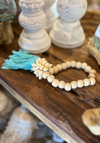 Natural bead with turquoise tassel decoration and shell detail.