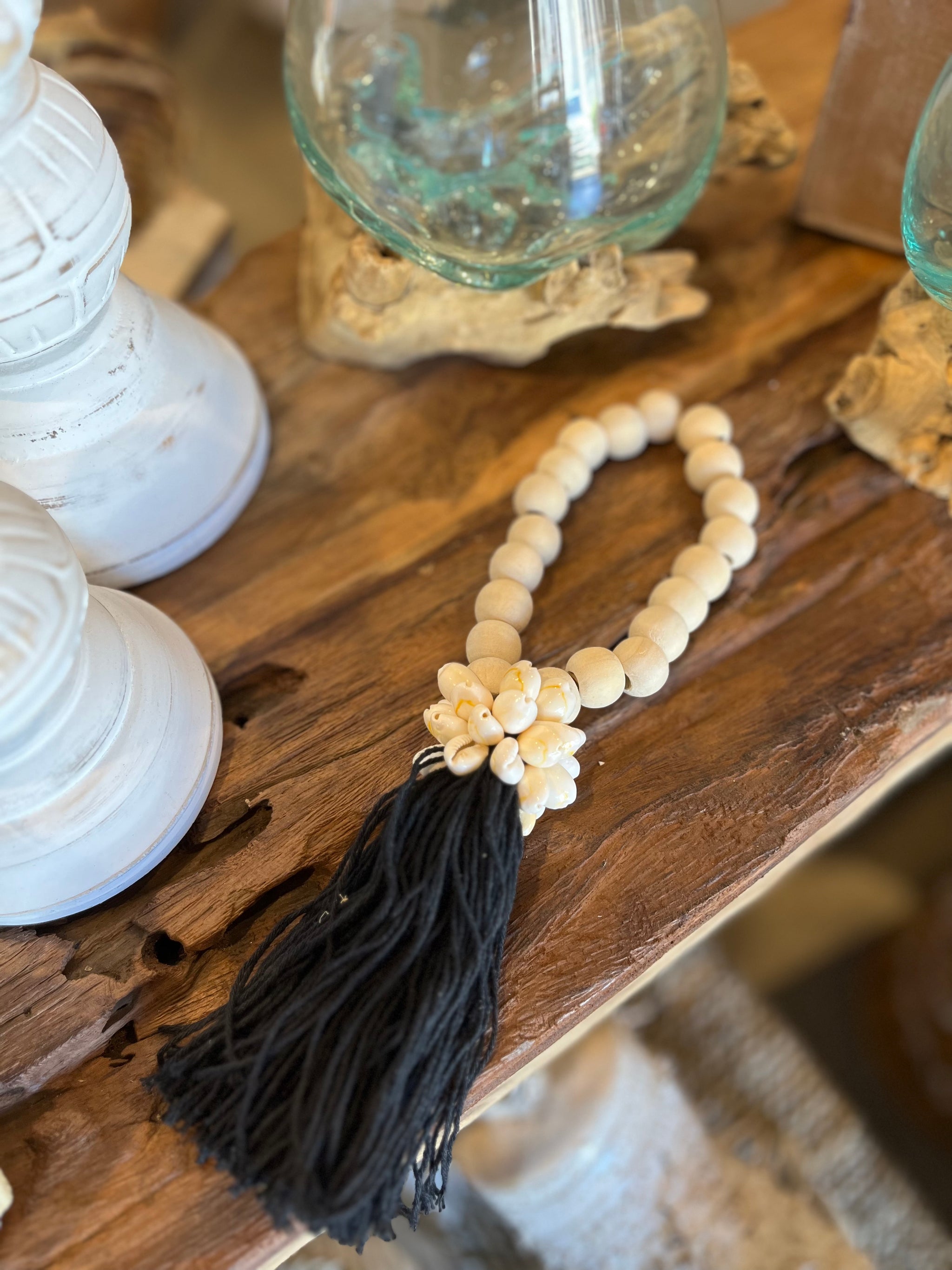 Natural bead with black tassel decoration and shell detail.