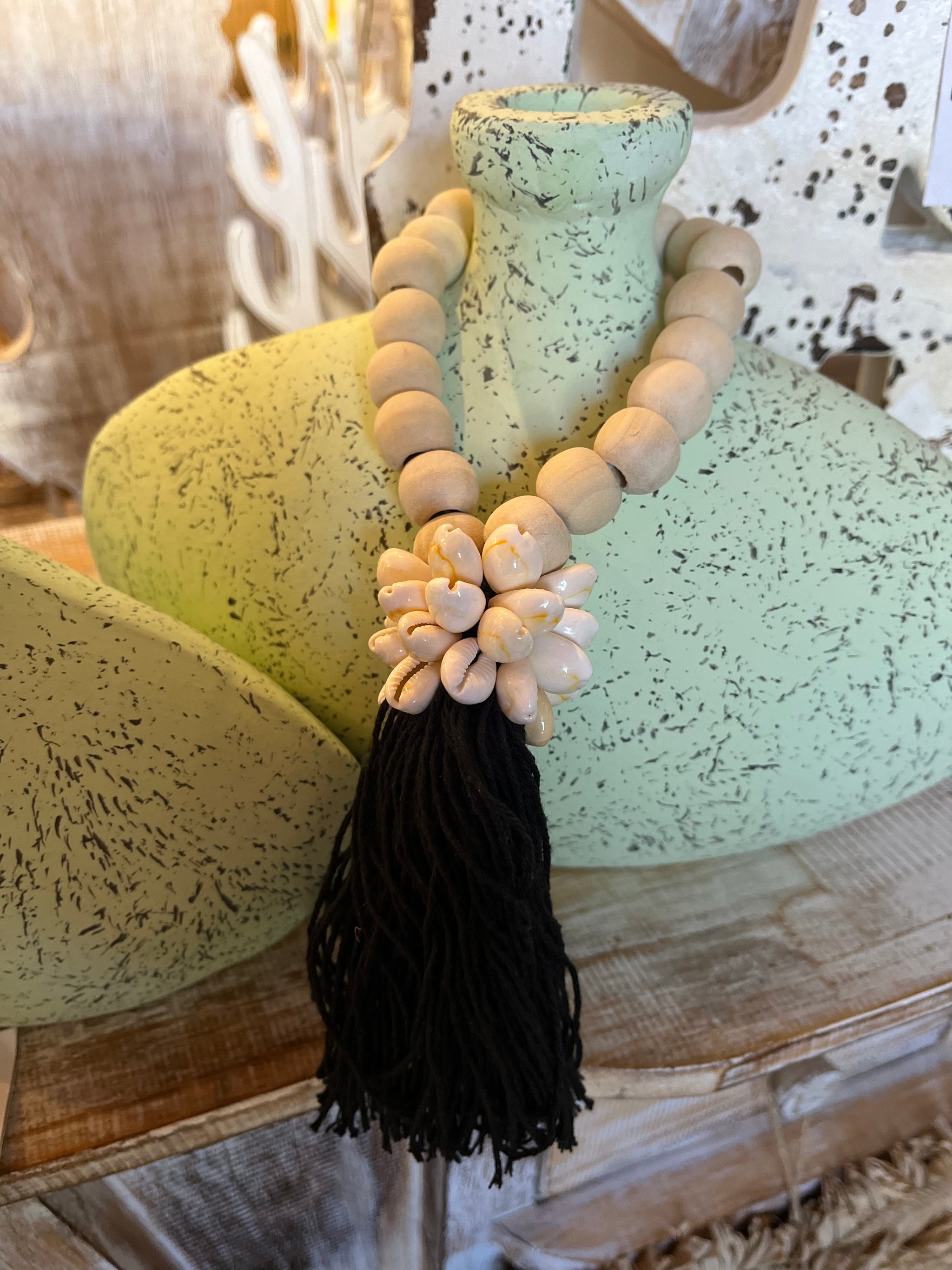 Natural bead with black tassel decoration and shell detail.