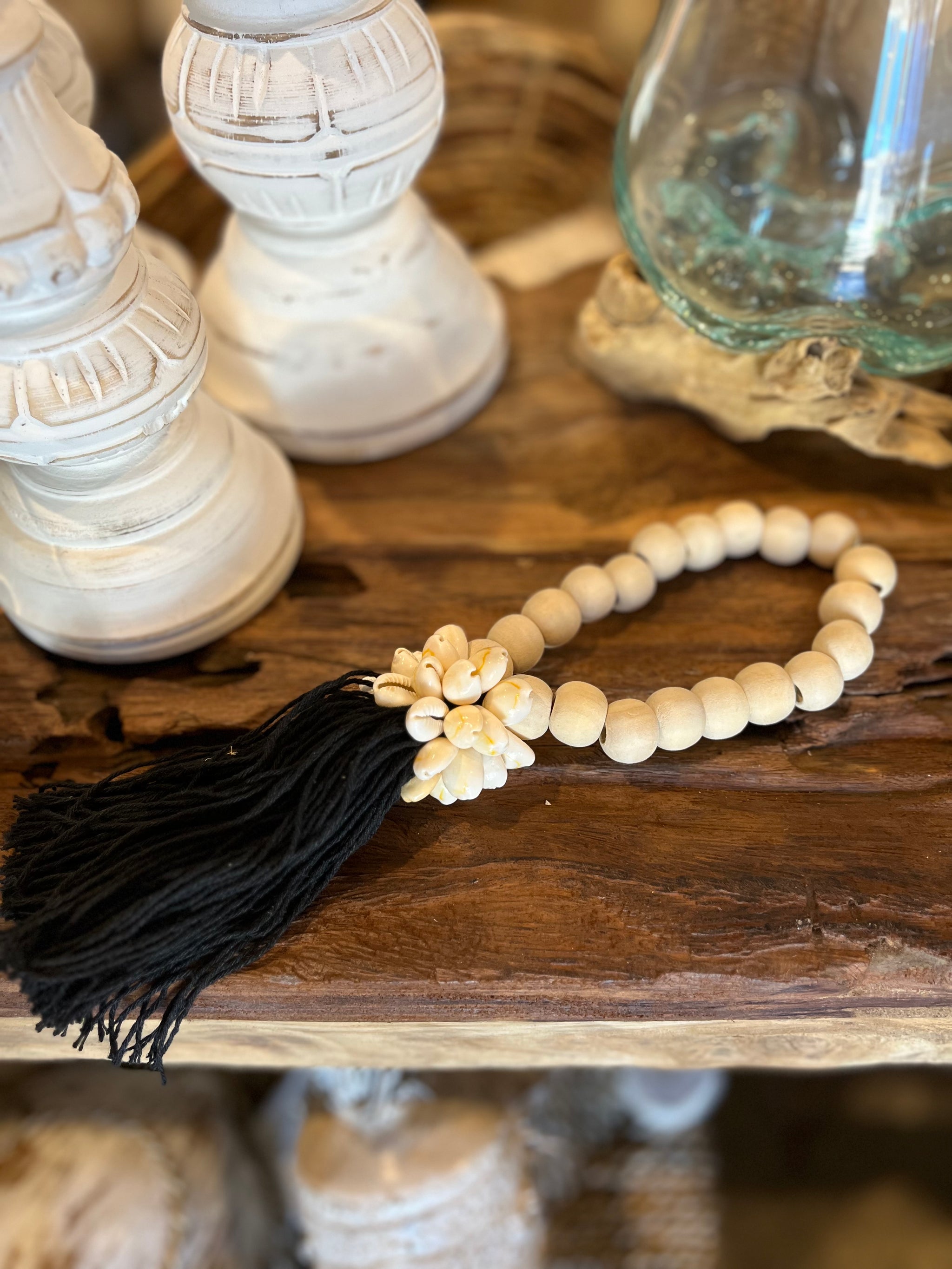 Natural bead with black tassel decoration and shell detail.