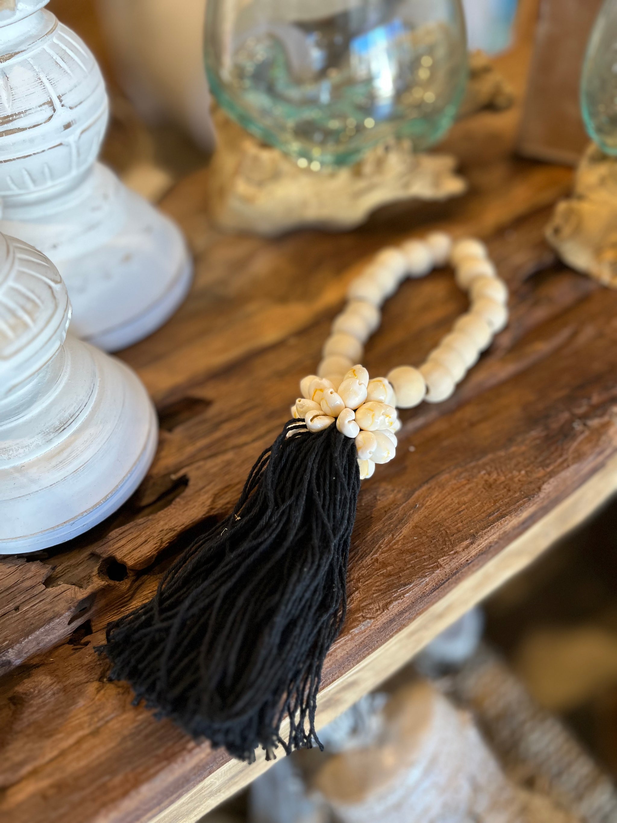 Natural bead with black tassel decoration and shell detail.