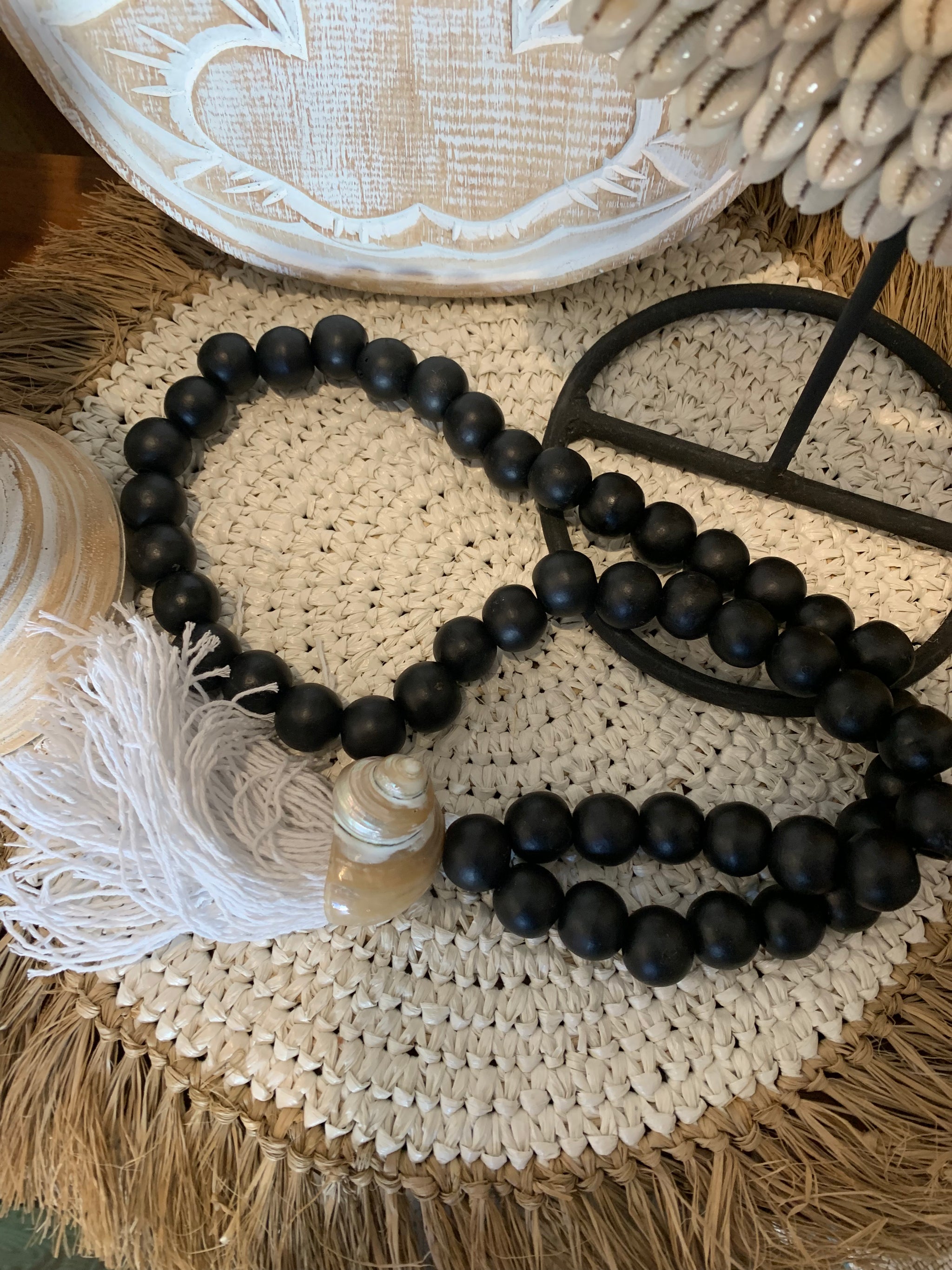 Black bead necklace / tassel decoration with shell detail and white tassel.