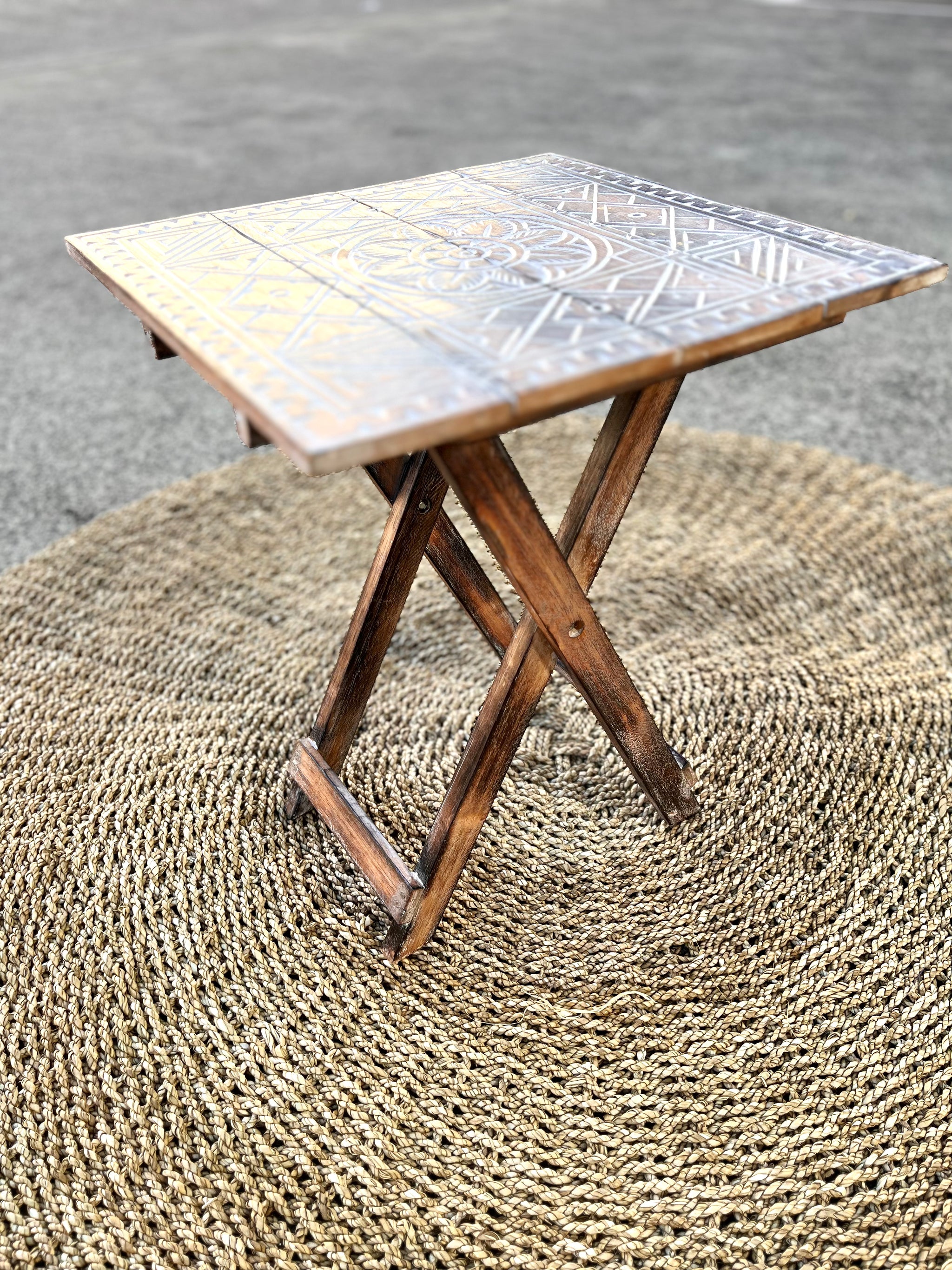 Folding timber carved design table. Brown finish. 49cm h